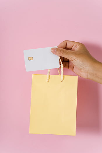 クレジットカード、 小さな紙袋、 オンラインショッピング、 ピンクの背景、 黄色いショッピングバッグ、 手持ち、 閉じる、 白い銀行カード、 ショッピングの概念、 電子商取引、 消費主義