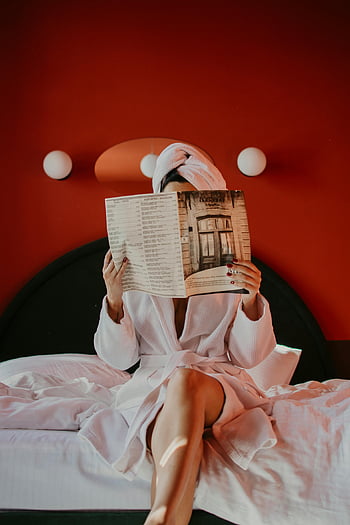 Frau liest Magazin, Bademantel, Gemütliches Hotelzimmer, Bett, rote Wand, Zeitschrift, Hotel, Entspannung, lesen, Bademantelstil, Gemütliche Atmosphäre