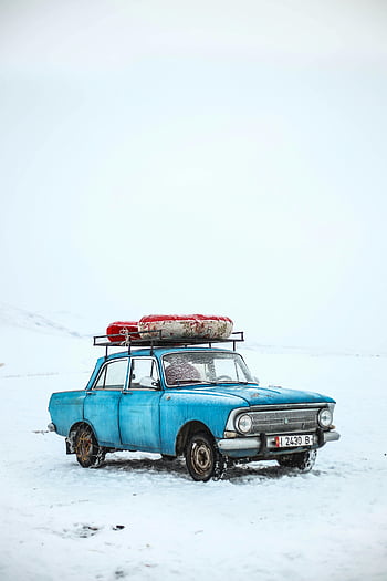 blue box-type sedan, classic blue car, snowy winter scene, Ak-Talaa District, Kyrgyzstan, vintage car, snow-covered landscape, winter vehicle, outdoor winter photo, car with roof rack, lifebuoy on car