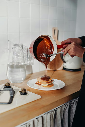 pannukakut, suklaasiirappi, kaatamalla, kodikas keittiö, kotitekoinen, aamiainen, elintarvikkeiden valokuvaus, keittiö, puinen työtaso, lasi syöttäjä, valkoiset laatat