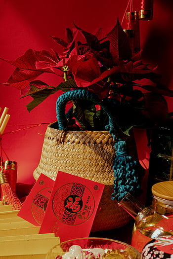 woven basket, red flowers, red envelopes, Vietnamese New Year, celebration, traditional decor, festive arrangement, cultural tradition, holiday decoration, red background, poinsettia flowers