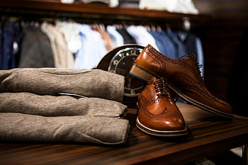 Hnědé kožené boty křídla, šedé oblečení, dřevěný povrch, Stylové kožené boty, Šedé oblečení, Nastavení elegantního butiku, Pánská móda, kožená obuv, butikový displej, pánské boty, šedé kalhoty