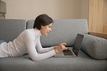nő használ laptop, távoli munka, A kanapén fekve, otthoni munkavégzés, otthonról dolgozik, laptop a kanapén, Kényelmes munkaterület, alkalmi munkakörnyezet, Nő távolról dolgozik, otthoni munka, Hangulatos munka beállítása