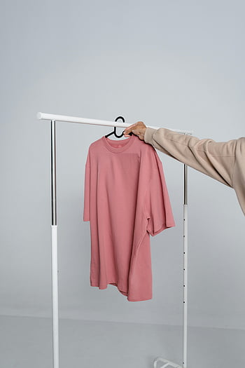 ピンクのTシャツ、 シャツを持っている人、 衣類用ラック、 ファッションデザイン、 モックアップ、 長袖シャツ、 ハンガー、 ミニマリストの背景、 カジュアルウェアー、 衣料品ディスプレイ、 ファッション写真