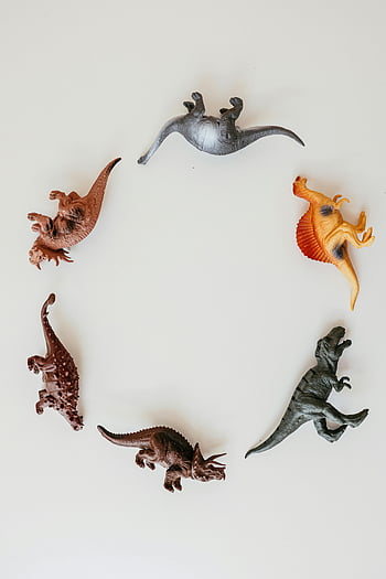 dinosaur toys, circle arrangement, colorful dinosaurs, white surface, playful decor, toy dinosaurs, round arrangement, white backdrop, dinosaur figures, decorative toys, kids toys