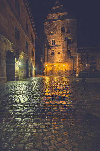 medieval tower, historic old town, illuminated cobblestone streets, nighttime street view, gothic architecture, street lamp, European architecture, historic landmark, tourist destination, night photography, quaint