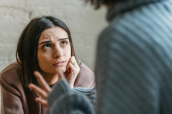 sad woman, serious conversation, indoor setting, thoughtful listening, conflict, anonymous woman, emotional expression, indoor dialogue, serious discussion, indoor interaction, emotional moment