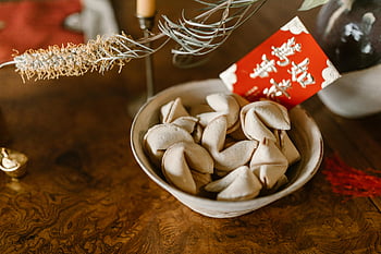 fortune cookies, red envelope, ceramic bowl, wooden table, traditional red envelope, Chinese culture, festive table setting, holiday decoration, good luck, New Year celebration, fortune telling