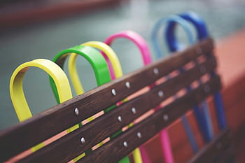 panca di design colorata, maniglie dai colori vivaci, panca moderna in legno, ambientazione del parco urbano, maniglie colorate per panche, design moderno della panca, panchina del parco urbano, maniglie vibranti della panca, panca di legno colorata, panchina urbana moderna, panca dal design vibrante