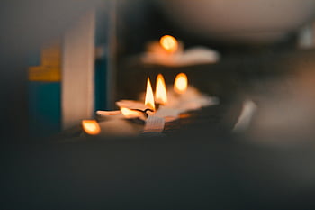 candle flames, selective focus, lighted tealights, warm atmosphere, close-up photography, flickering candles, candlelight, cozy ambiance, soft lighting, candle wax, candle holder