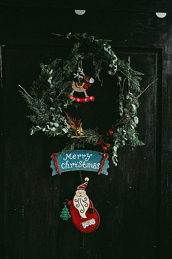 Christmas wreath, green wreath, door decoration, rustic wreath, seasonal decorations, Merry Christmas sign, dark door, holiday decor, festive wreath, Christmas ornament, Santa decoration