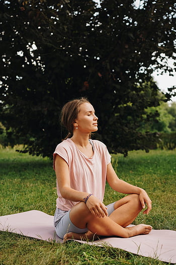 nő meditál, rózsaszín inget, jógamatrac, szabadtéri meditáció, derűs park, csukott szemmel, békés környezet, természetes környezet, éberségi gyakorlat, egészséges életmód, relaxációs technika
