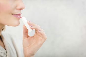 pink lip balm, woman applying lip balm, close-up, lip care, lip protection, young woman, skincare, beauty, makeup, cosmetics, health