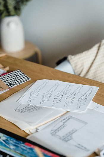 Skitser på bordet, værksted, Kreativ modedesign, arbejdsområde, Stofprøver, træbord, Modeskitser, Design arbejdsområde, Stoffanger, Fashion designproces, kreativt arbejdsområde
