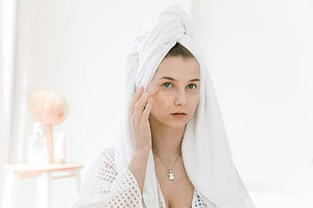 wanita, mantel mandi, produk perawatan kulit, dalam ruangan yang cerah, handuk di kepala, mengaplikasikan krim, rutinitas kecantikan, rutinitas pagi hari, perawatan diri, perawatan wajah, perawatan kulit