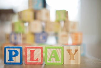 depth of field, wooden letter decors, beige wooden surface, colorful wooden blocks, spelling PLAY, educational themes, close-up photography, wooden blocks, PLAY letters, educational toys, children's toys