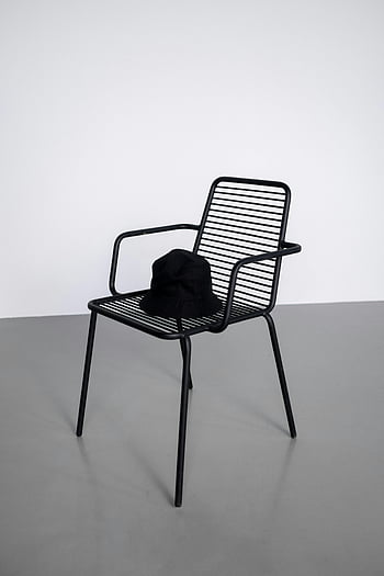 cappello secchio, sedia di metallo, sedia in metallo nero, girato in studio, sfondo bianco, Eleganza moderna, cappello nero, design minimalista, fotografia al coperto, accessorio di moda, Stile Contemporaneo