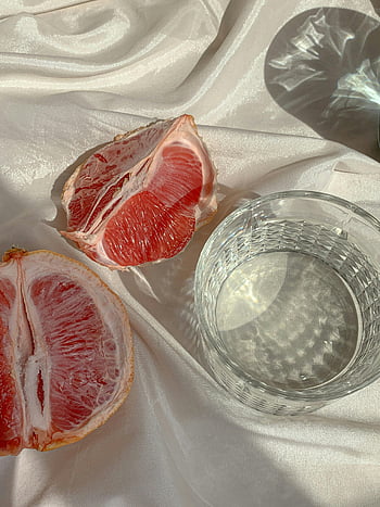 grapefruit, plátky grapefruitu, sklenice vody, bílý povrch, saténový povrch, odrazy světla, detail, ovocné fotografie, stálý život, zdravé jídlo, osvěžující nápoj