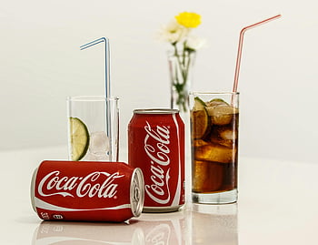Coca-Cola cans, glasses with straws, ice and lime, fresh drinks, invigorating beverages, table setting, soda cans, refreshing drinks, lime garnish, cold beverages, drink photography