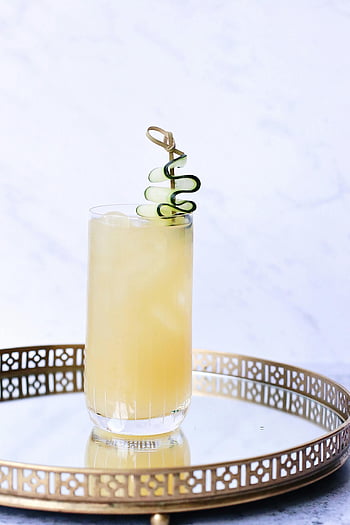 Glas kaltes Gingergetränk, Zierschale, hohes Glas, Erfrischendes Zitrusgetränk, Gurkenspirale, Dekorative Tablett, garniertes Getränk, Zitrusgetränk, Gurkengarnitur, Zahnstockschale, Erfrischungsgetränk