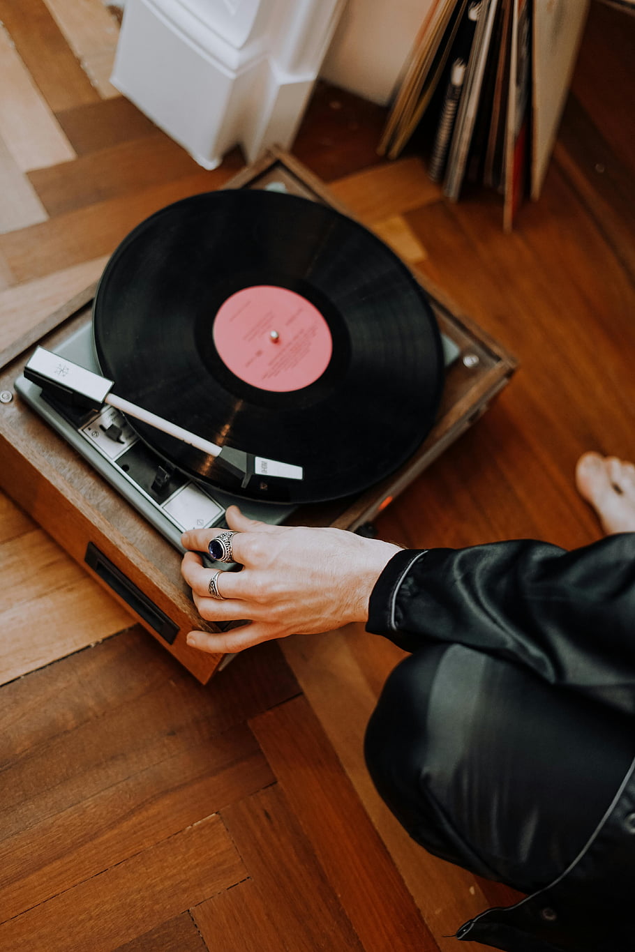 starožitný gramofon, Vintage gramofon, gramofonová deska, dřevěná podlaha, Vnitřní nastavení, Úprava osoba, Retro zvuk, poslech hudby, Klasické zvukové vybavení, ruka na točna, přehrávač
