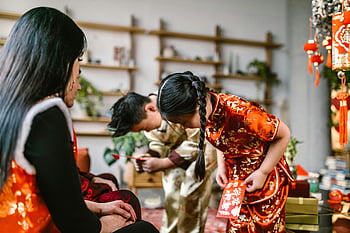 Chinesisches Neujahr, traditionelle Kleidung, Rote Umschläge, Familientreffen, Innenfeier, Jungen verbeugt, Mädchen verbeugt sich, kulturelle Tradition, festliche Anlass, Home -Einstellung