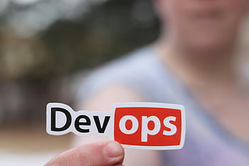 DevOps sticker, person holding, close-up image, outdoors, DevOps, sticker, hand holding, outdoor setting, technology sticker, software development, IT industry