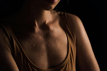 wet skin, water droplets, close-up, dark background, woman's chest, wet chest, close-up photo, wet skin texture, water drops, dark backdrop, woman's wet skin