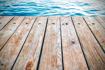 braunes hölzernes Dock, rustikaler Holzpier, strukturierte Bretter, ruhiges blaues Wasser, Gelassene Natur, detaillierte Ansicht, Holzbretter, Naturthemen, stilles Wasser, rustikales Dock, Holzsteg