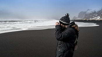 sort sandstrand, havbølger, skyet dag, fotograf, beanie cap, jakke, Slående strand, tager billeder, udendørs fotografering, vinter tøj, kystlandskab