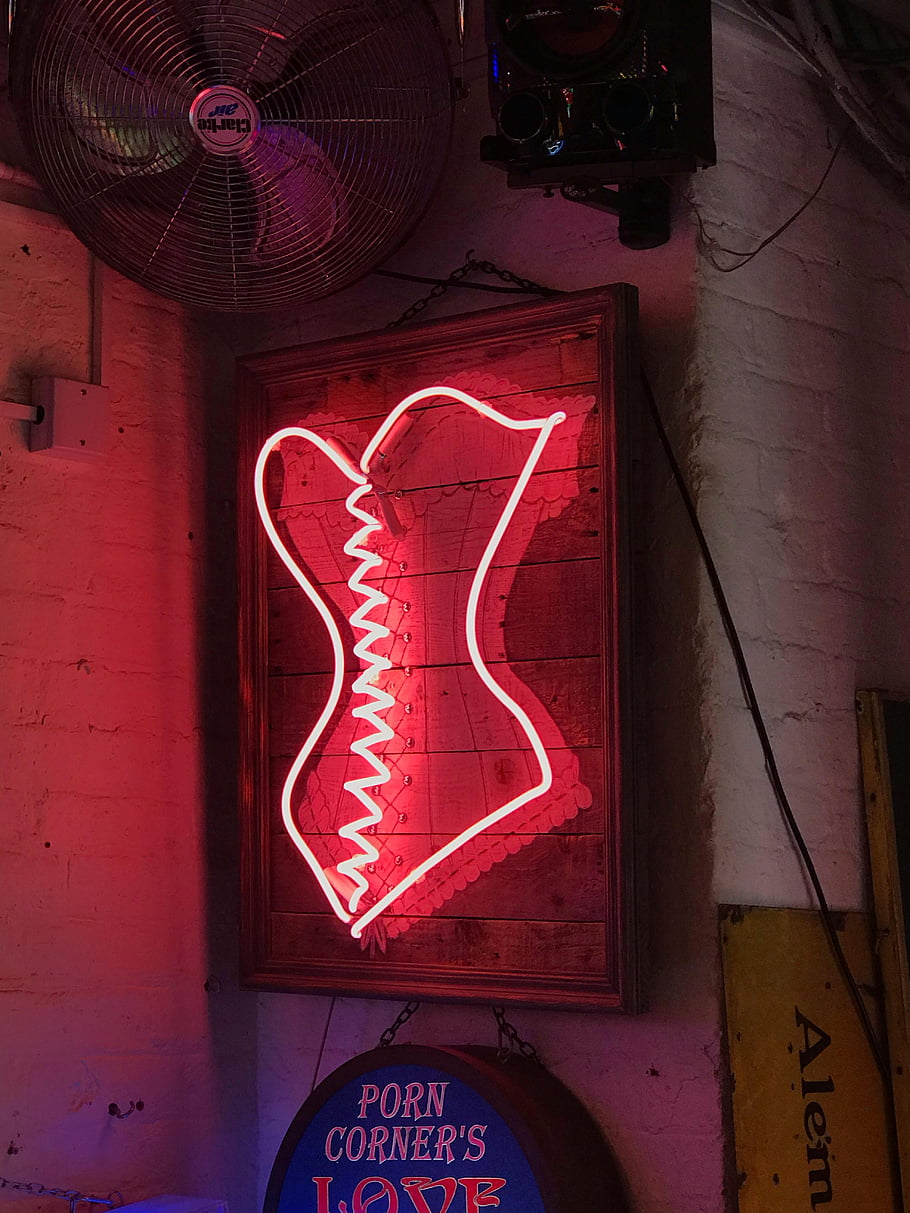 neonové světlo značení, neonový nápis korzet, cihlová zeď, retro vibe, Disly osvětlený bar, interiér, neonový nápis, bar interiér, neonová výzdoba, vinobraní znamení, neonové umění