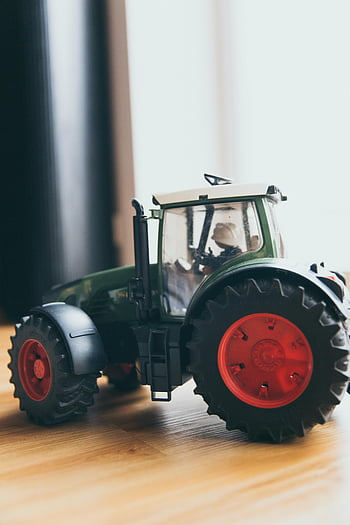 Mainan traktor hijau, roda merah, Traktor Miniatur, permukaan kayu, mainan close-up, Detail mainan, hijau dan merah, model traktor, kendaraan mainan, mainan dalam ruangan, fotografi mainan