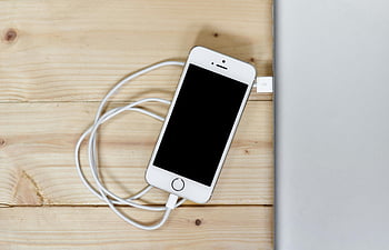 silver iPhone 5s, charging cable, wooden surface, smartphone, Apple device, tech gadget, mobile phone, charging port, electronic device, white cable, technology