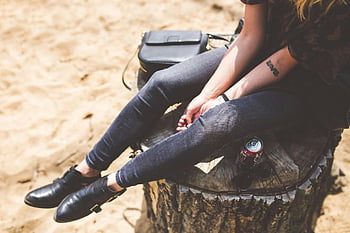 blue denim jeans, black leather shoes, sitting on trunk, casual fashion, sunny day, drink, bag, sunglasses, woman seated, trunk, casual style