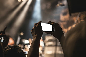 concierto, teléfono inteligente, música en vivo, capturando, escena vibrante, manos sosteniendo, teléfono inteligente negro, experiencia en concierto, audiencia, luces de escenario, fotografía de eventos