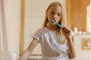 girl brushing teeth, daily dental care, young girl, toothbrush, bathroom, dental hygiene, healthy habits, morning routine, oral health, white shirt, blonde hair