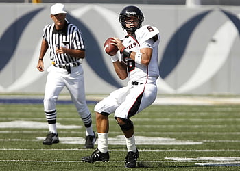football player, holding football, referee, outdoor game, athlete in uniform, preparing to throw, football game, sports action, field, uniform, helmet