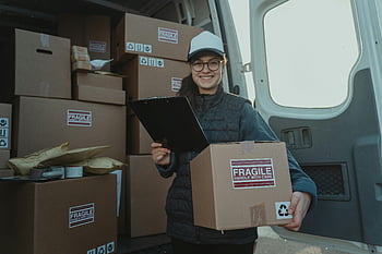 female courier, carrying box, holding clipboard, cheerful delivery woman, preparing parcels, inside van, careful handling, fragile handle with care, delivery service, professional delivery, van interior