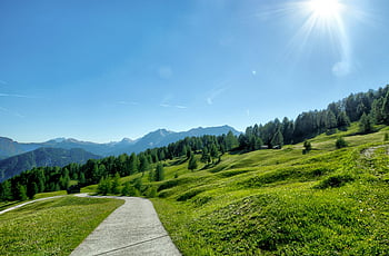 zelené trávy, Klidná horská krajina, Slunečná cesta, živá zeleň, Majestátní vrcholy, horský výhled, slunečný den, přírodní scenérie, Venkovní krása, scénická cesta, Svěží zelená pole