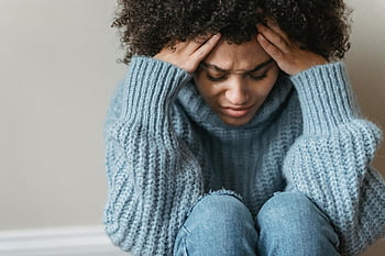Træt sort kvinde, krøllet hår, Hyggelig sweater, indendørs, tankevækkende, eftertænksom, rørende hoved, ser ned, ung kvinde, Trist udtryk, følelsesmæssigt øjeblik