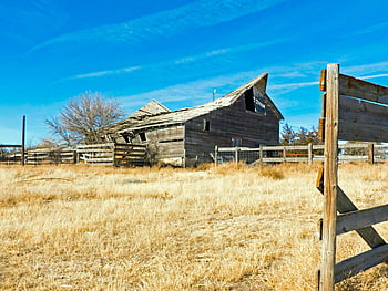 brown wooden barn, dilapidated barn, rural setting, vivid blue sky, wooden fence, farm scene, old barn, countryside landscape, abandoned barn, rural landscape, wooden structure