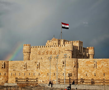 Citadel of Qaitbay, Alexandria, Egypt, rainbow backdrop, stunning view, historic fortress, Egyptian flag, ancient architecture, tourist attraction, Mediterranean coast, Middle East travel