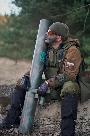 man in camouflage, holding rifle, soldier, forest setting, combat ready, large weapon, green and brown uniform, military gear, tactical equipment, outdoor scene, camouflage uniform