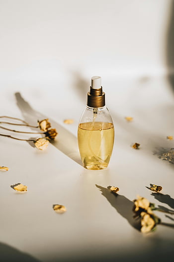 perfume bottle, white surface, dried flowers, minimalist setting, product photography, stylish perfume, floral arrangement, fragrance bottle, white background, dried petals, aesthetic composition