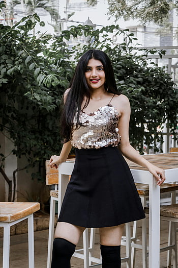 Top de paiete, fusta neagra, urban fashion, fundal de verdeață, ținută la modă, Pozând în aer liber, genunchi-șosete înalte, femeie elegantă, stil modern, Chic casual, aspect de oraș