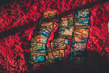 tarot cards, red fabric, mystical themes, fortune-telling, textured fabric, card reading, divination tools, esoteric symbols, spiritual practice, occult imagery, card layout