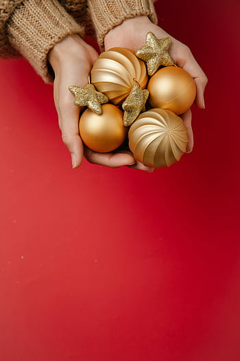 Altın Noel Baubles, Süsleri tutan eller, şenlikli kırmızı arka plan, yılbaşı ağacı süsleri, altın takılar, tatil dekoru, Noel süsleri, bayram süslemeleri, Altın Toplar, Noel baubles, şenlikli süslemeler