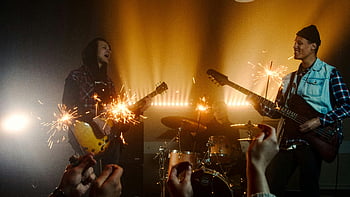 Banda en vivo, guitarras, bengalas, atmósfera vibrante, concierto, guitarra electrica, bajo, tambores, actuación, energético, celebracion