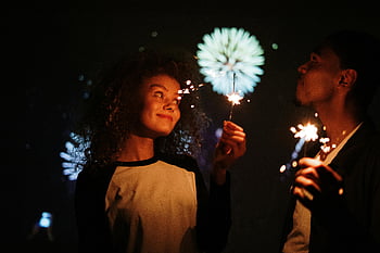 pareja sosteniendo bengalas, pareja joven, celebrando, bengalas, fuegos artificiales, noche, festivo, momento alegre, celebración al aire libre, escena romantica, Celebración navideña