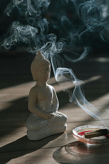 Buddha figurine, Palo Santo, burning wood, serene smoke, calm ambiance, holy wood, meditation, spiritual, incense, tranquility, statue